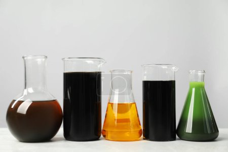 Photo for Laboratory glassware with different types of oil on white table - Royalty Free Image