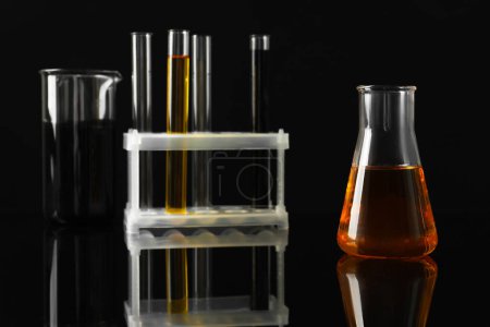 Photo for Laboratory glassware with different types of oil on black background, closeup - Royalty Free Image