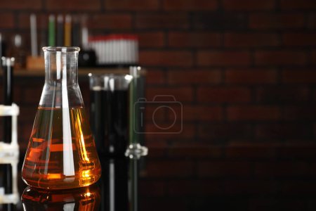 Photo for Laboratory glassware with different types of oil on black mirror table indoors, closeup. Space for text - Royalty Free Image