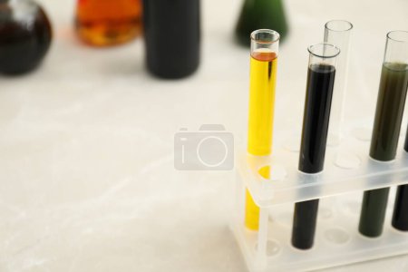 Photo for Test tubes with different types of crude oil on light marble table, space for text - Royalty Free Image