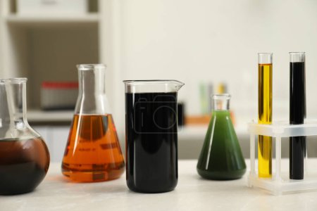 Photo for Laboratory glassware with different types of crude oil on light marble table - Royalty Free Image