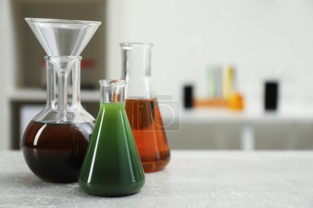 Photo for Laboratory glassware with different types of crude oil on light grey table, space for text - Royalty Free Image