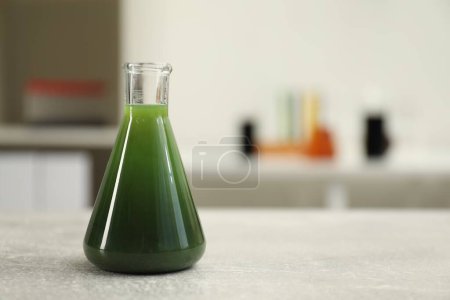Photo for Flask with green crude oil on light grey table, space for text - Royalty Free Image