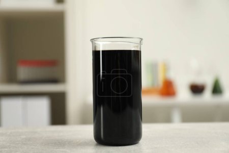 Photo for Beaker with black crude oil on light grey table - Royalty Free Image