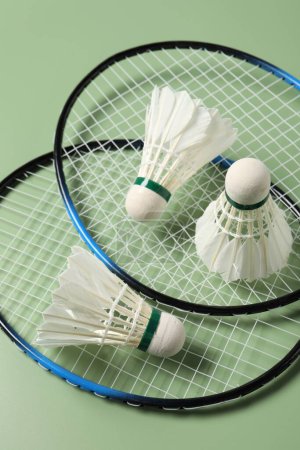 Photo for Feather badminton shuttlecocks and rackets on green background, above view - Royalty Free Image