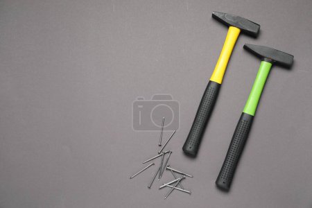 Hammer and metal nails on grey background, top view. Space for text