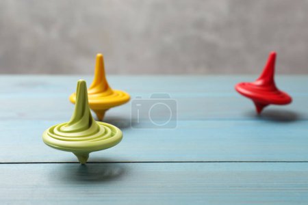 Photo for Bright spinning tops on light blue wooden table, closeup - Royalty Free Image