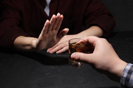 Téléchargez les photos : L'alcoolisme. Femme refusant un verre de whisky à table noire, gros plan - en image libre de droit