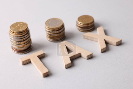 Word Tax made of wooden letters and coins on white background