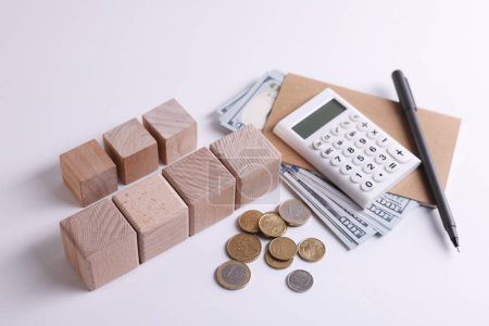 Taxes. Wooden cubes, calculator, coins and banknotes on white background