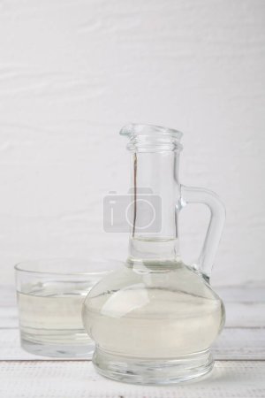 Foto de Vinagre en jarra de vidrio y tazón sobre mesa de madera blanca - Imagen libre de derechos