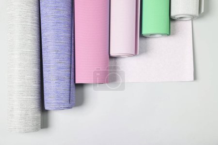 Different wallpaper rolls on light grey background, flat lay
