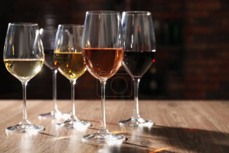 Photo for Different tasty wines in glasses on wooden table, space for text - Royalty Free Image