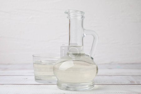 Foto de Vinagre en jarra de vidrio y tazón sobre mesa de madera blanca - Imagen libre de derechos