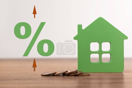 Hypothekenzinsen. Modell des Hauses, Münzen, Pfeile und Prozentzeichen