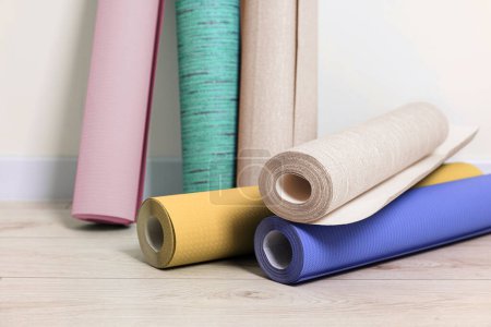 Photo for Colorful wallpaper rolls on light wooden floor in room - Royalty Free Image