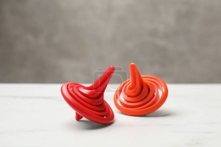 Photo for Bright spinning tops on white table, closeup - Royalty Free Image