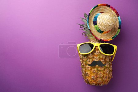 Téléchargez les photos : Ananas avec chapeau de sombrero mexicain, fausse moustache et lunettes de soleil sur fond violet, plat. Espace pour le texte - en image libre de droit