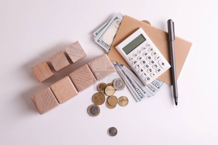 Taxes. Wooden cubes, calculator, coins and banknotes on white background, top view