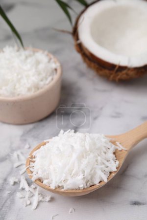 Photo for Coconut flakes in wooden spoon on white marble table - Royalty Free Image