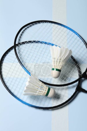 Photo for Feather badminton shuttlecocks and rackets on light blue background - Royalty Free Image