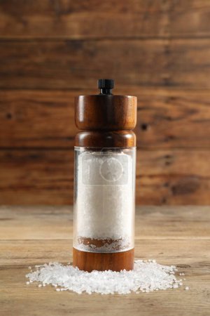 Photo for Shaker with salt on wooden table, closeup - Royalty Free Image