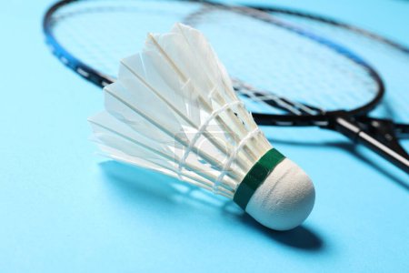 Photo for Feather badminton shuttlecock and rackets on light blue background, closeup - Royalty Free Image