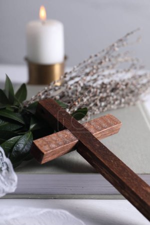Livre, croix et branches de saule sur table blanche, gros plan