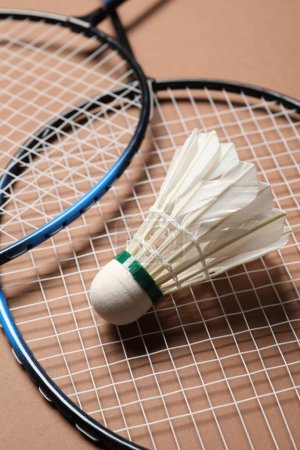Photo for Feather badminton shuttlecock and rackets on brown background, closeup - Royalty Free Image