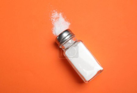 Photo for Salt shaker on orange table, top view - Royalty Free Image