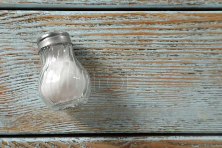 Photo for Salt shaker on light blue wooden table, top view. Space for text - Royalty Free Image