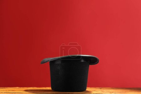 Sombrero de mago sobre mesa de madera sobre fondo rojo