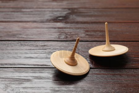 Two spinning tops on wooden table, closeup. Space for text