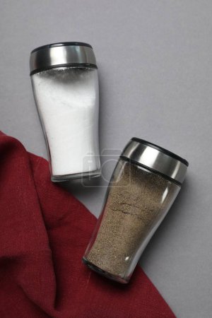 Salt and pepper shakers on grey table, flat lay