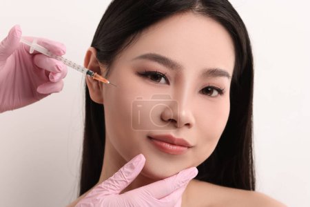 Mujer recibiendo inyección facial sobre fondo blanco