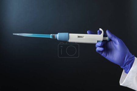 Photo for Laboratory analysis. Scientist holding micropipette with liquid on dark background, closeup - Royalty Free Image