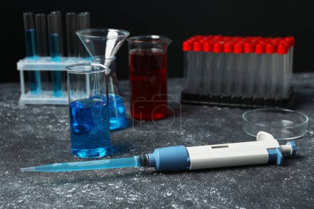 Photo for Laboratory analysis. Micropipette, beakers, flask, petri dish and test tubes on grey table - Royalty Free Image