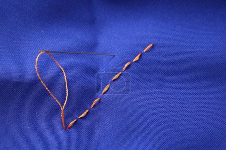 Téléchargez les photos : Aiguille à coudre avec fil et points de suture sur tissu bleu, vue ci-dessus - en image libre de droit