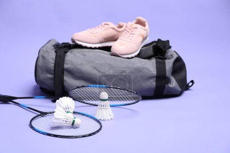 Photo for Feather badminton shuttlecocks, rackets, bag and sneakers on violet background - Royalty Free Image