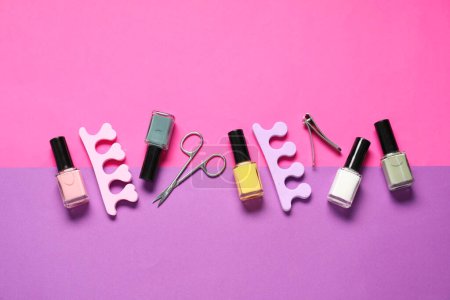 Nail polishes, clippers, scissors and toe separators on color background, flat lay