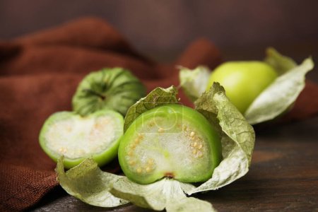 Fresh green tomatillos with husk on wooden table, closeup