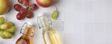 Different types of vinegar and ingredients on light tiled table, flat lay. Space for text