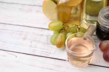Different types of vinegar and grapes on wooden table, closeup. Space for text