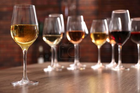 Photo for Different tasty wines in glasses on wooden table - Royalty Free Image