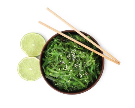 Tasty seaweed salad in bowl, chopsticks and pieces of lime isolated on white, top view