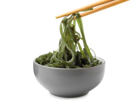 Taking tasty seaweed salad from bowl on white background