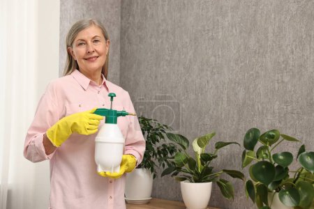 Glückliche Hausfrau mit Pflanzmeister bei grünen Zimmerpflanzen zu Hause
