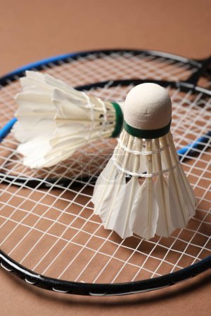 Photo for Feather badminton shuttlecocks and rackets on brown background, closeup - Royalty Free Image