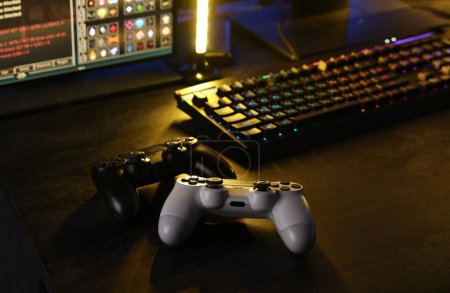 Videospiele spielen. Computermonitor, Tastatur und drahtlose Controller auf dem Tisch in Innenräumen