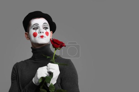 Porträt des Pantomimen mit roter Rose auf grauem Hintergrund. Raum für Text
